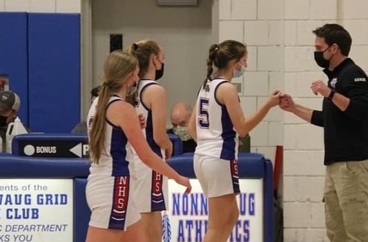 Adam Brutting, right, greets Nonnewaug basketball player Ella Lupo (5) and her teammates as they come off the floor during a game. Brutting inspires his basketball players and eighth-grade students with his win the day attitude.