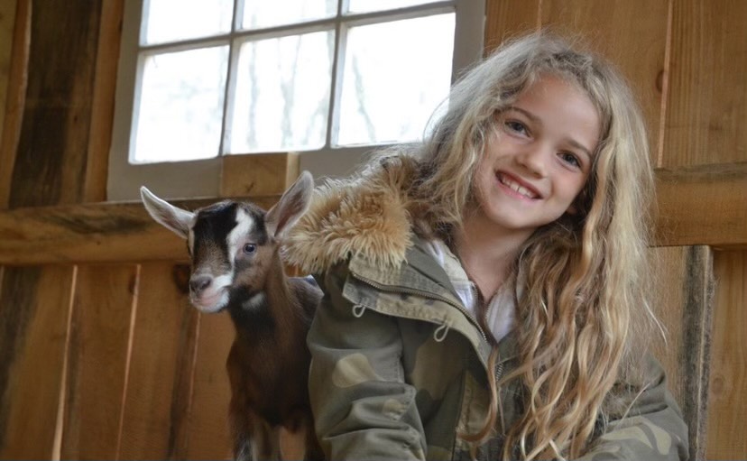A young Danni Syrotiak poses with one of her baby goats.