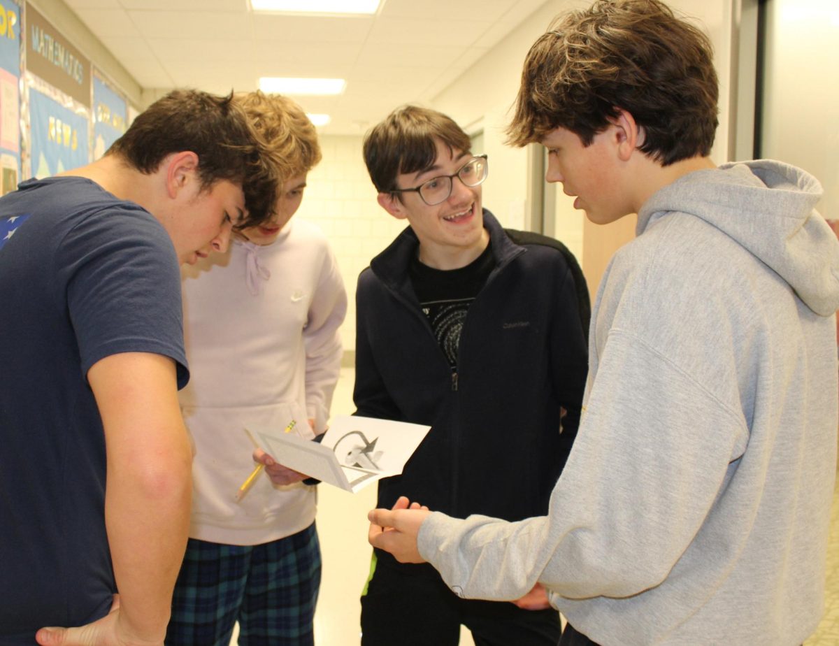 From left, sophomores Nic Sniffin, James Wolf, Isaac Stevens, and Ethan Wild work to solve one of the clues during the red-out scavenger hunt Feb. 9 at Nonnewaug.
