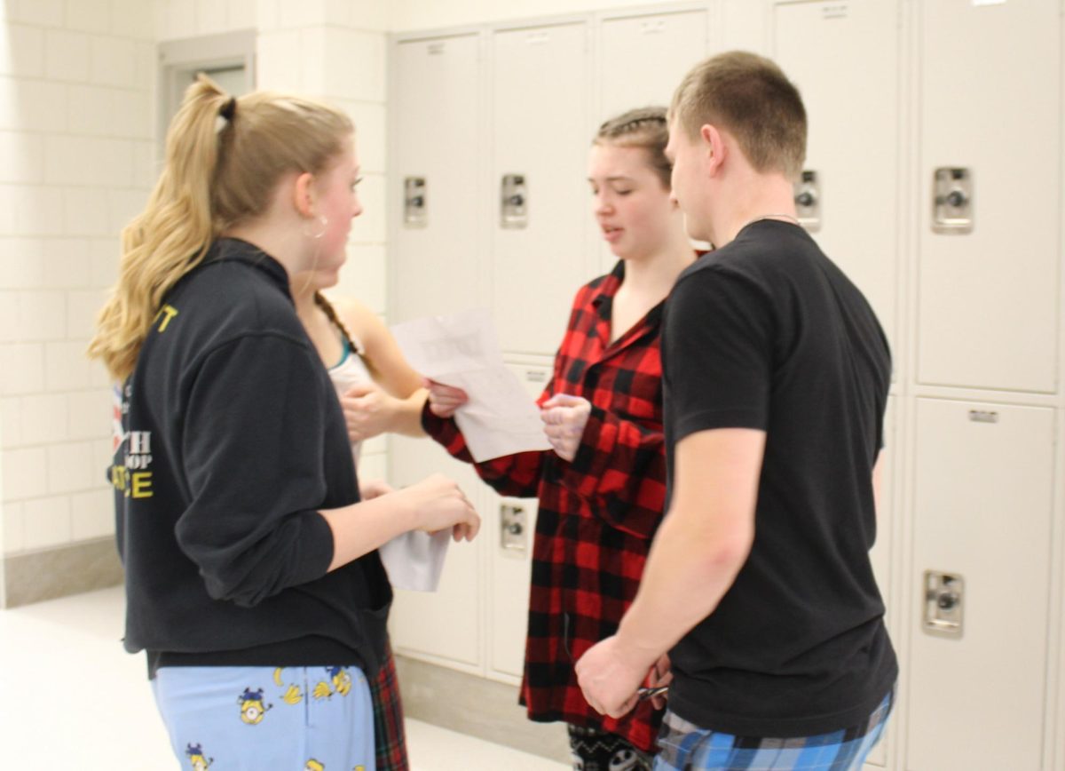 From left, freshmen Caitlin Frechette, Sadie Turchuk, Michael Lipinski work to solve a clue during the red-out scavenger hunt Feb. 9 at Nonnewaug.