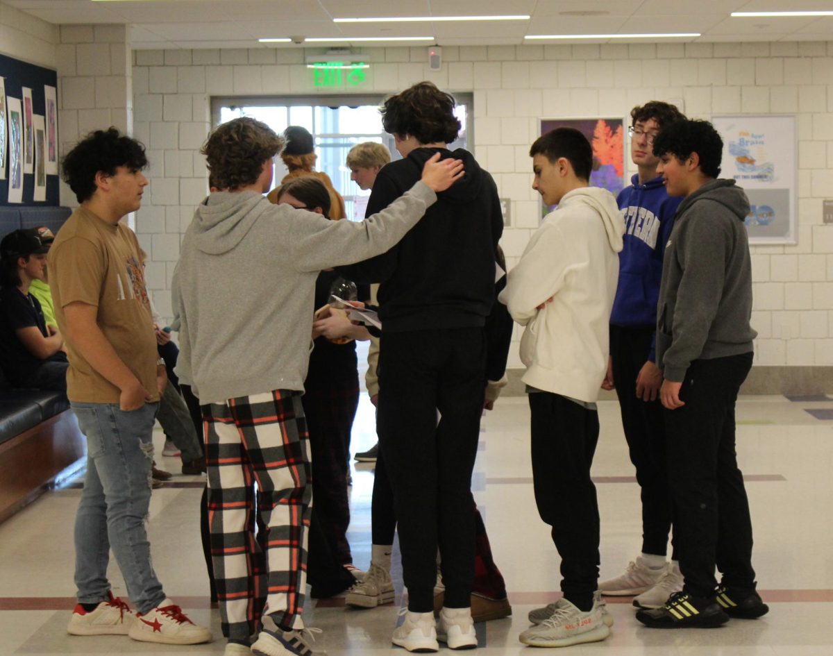 A freshman advisory huddles outside the auditorium to solve a clue during the red-out scavenger hunt Feb. 9 at Nonnewaug.