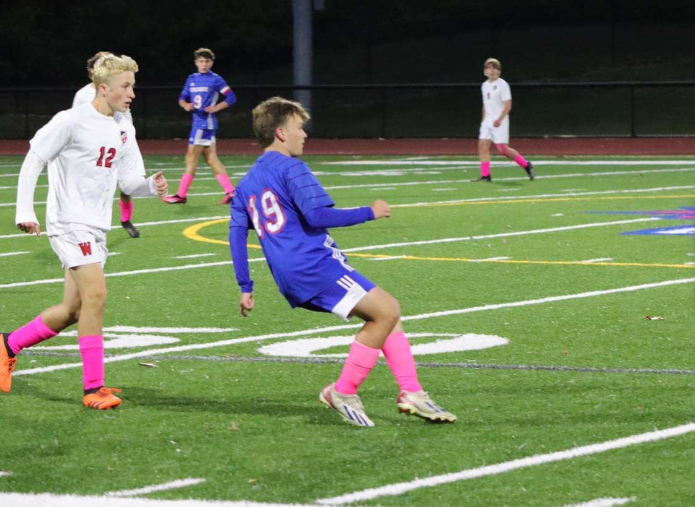 Carson Buck (19) passes the ball during Nonnewaugs night game against Wamogo. His contributions to the team go deeper than just a pass on the field: Buck is consistently there for his teammates. (Courtesy of Nonnewaug Boys Soccer/Facebook)