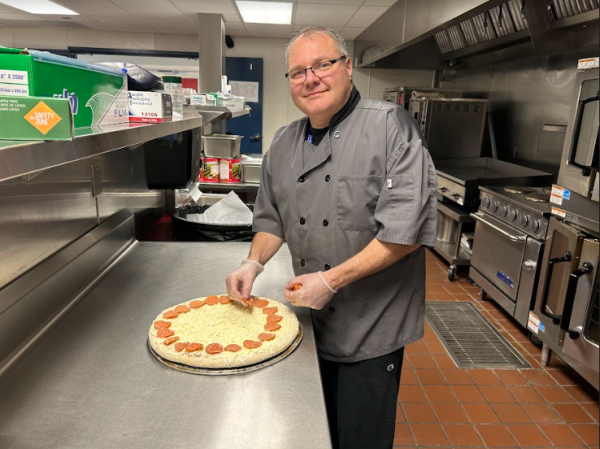 NHS cafeteria staff member Costa Lefkimiatis prepares a pepperoni pizza that will be served to hungry students.