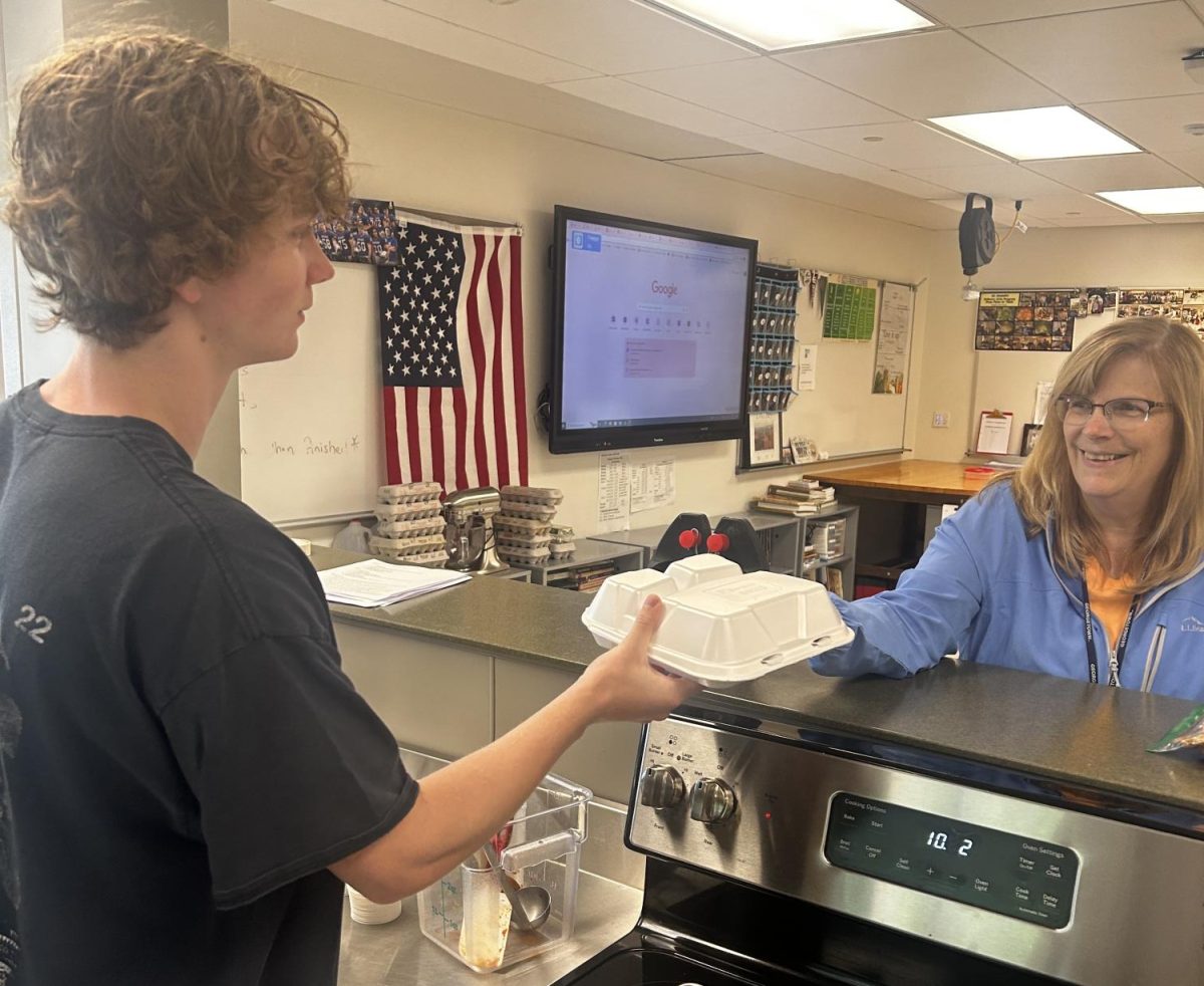 Senior Quinn Lenoard, left, delivers Ellie Bruce one of the bistro meals. NHS culinary arts department provides a variety of real-world experiences for students ranging from preparing for multiple Senior Citizen Meals, community food banks, and other special events on campus. 