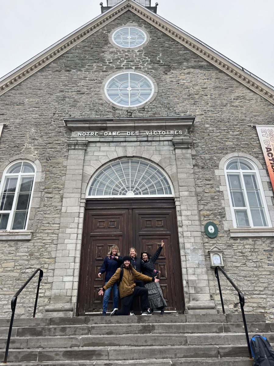 Chaperones Kathryn Brenner, Kate Peterson, and Sandy Snabaitis pose with the Quebec City tour guide Alec in front of the Notre Dame Church.