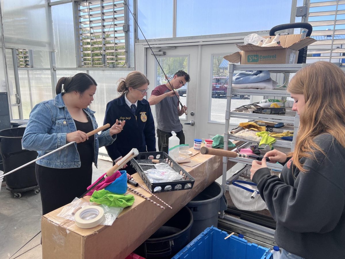 From left to right, aquaculture instructor Leanne Golembeski, Abby Diezel, Devon Zapatka and Jillian Brown work in the aquaculture greenhouse, hand-crafting cork handles for fishing poles for their fundraiser. 