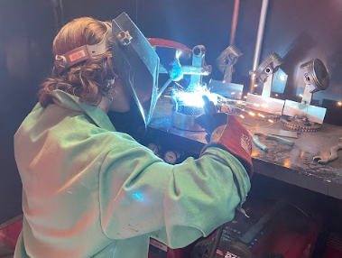 A masked Nonnewaug student enrolled in the agricultural mechanics course welds  prior to the Woodbury FFA Kickin Country Car, Truck, and Tractor Show on Oct. 1, 2023. These skills and others learned in the Nonnewaug ag program can be applied in various fields directly after graduation for students who choose not to pursue a college education. (Courtesy of Tom DiMarco)