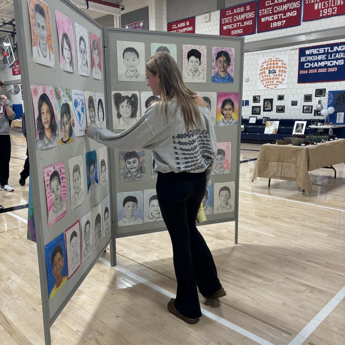 Deme Jones looks at students orphan portraits at Nonnewaug’s art show on June 6.