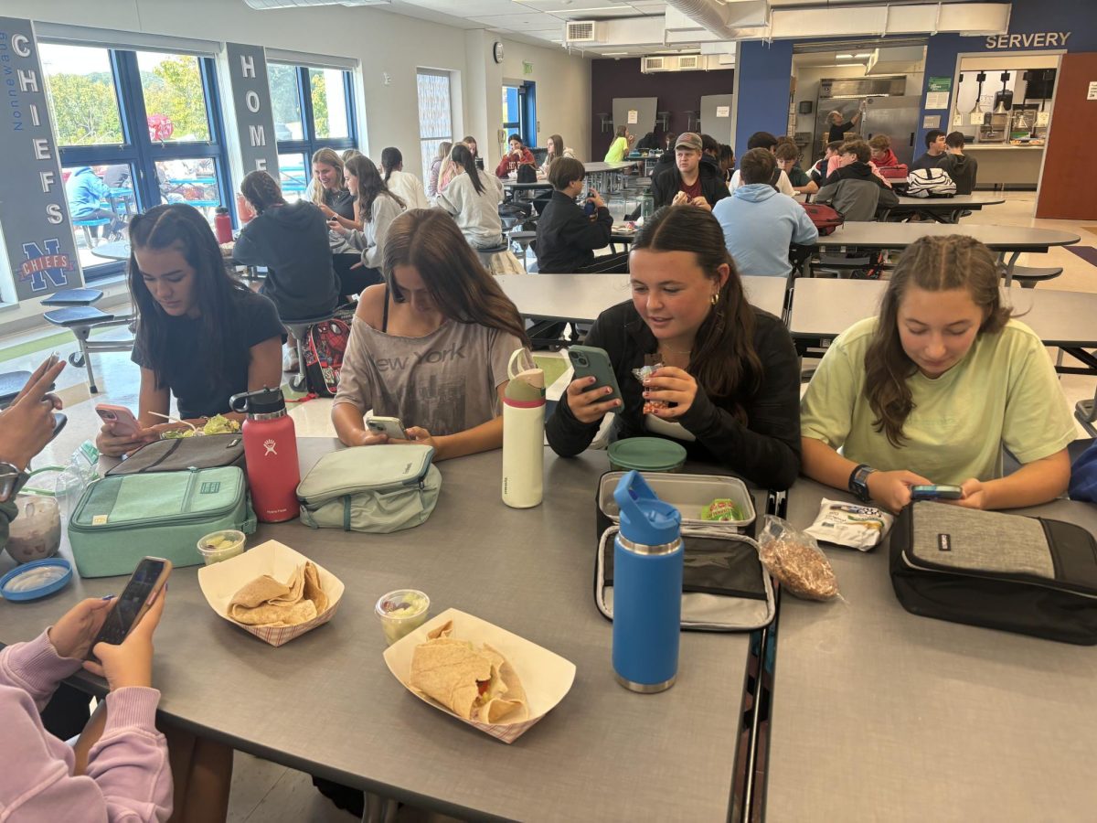 From left, Maddie Gargulio, Anna Walkup, Bryce Gilbert, Elliana Obolewicz use their phones at lunch instead of socializing.