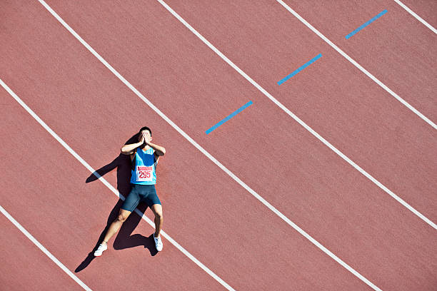 A track athlete lays on the track with a sorrowful gesture. Losing is a constant part of sports. (Courtesy of Paul Bradbury/Pixabay)