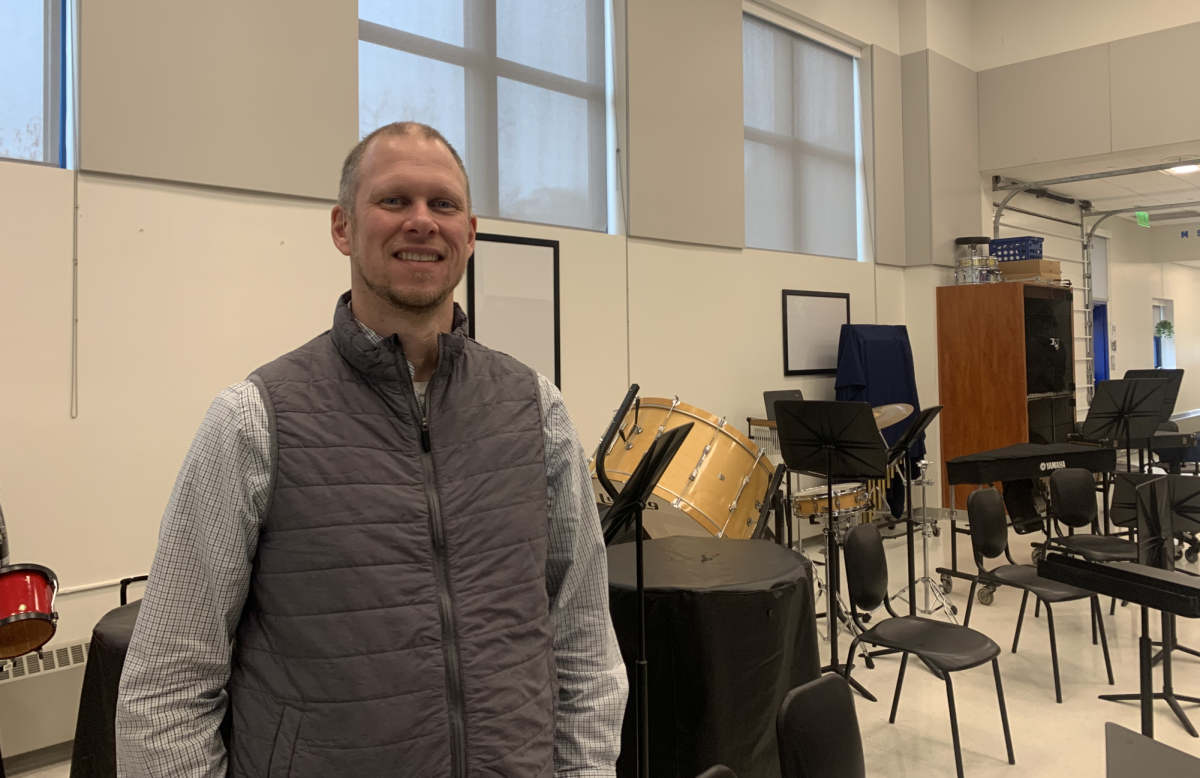 Todd Gorski, music teacher, stands in front of several instruments in the music suite at Nonnewaug.