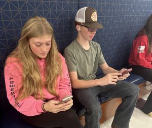 Cate Frechette, left, and Nasir Stevenson use their phones during study hall. As the year moves on, administrators and staff members are more strictly enforcing the cellphone policy.