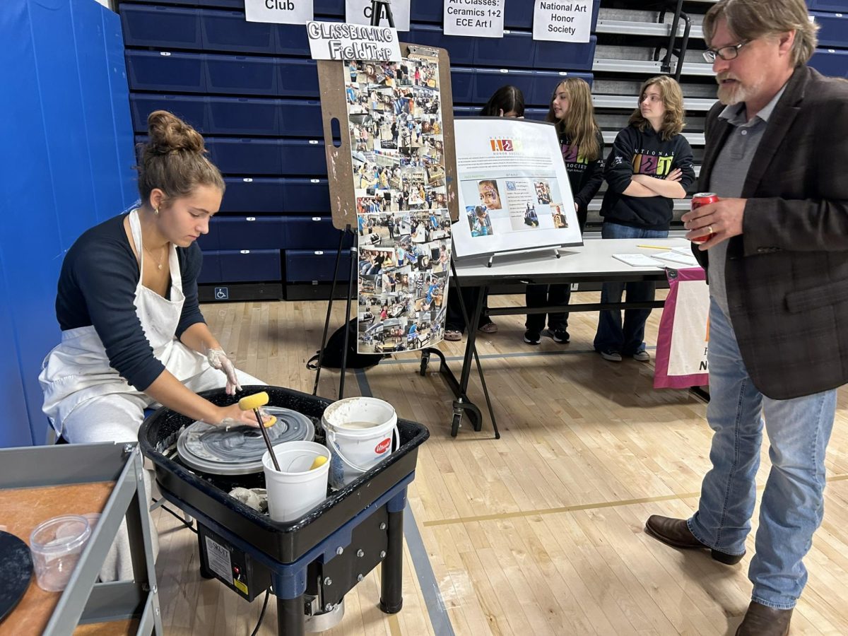 Ceramics student Molly Hartmann, left, works on the pottery wheel as social studies teacher Steve Bunovsky looks on during the Club, Activities, and Electives Fair on Sept. 26. (Courtesy of Kyle Brennan)