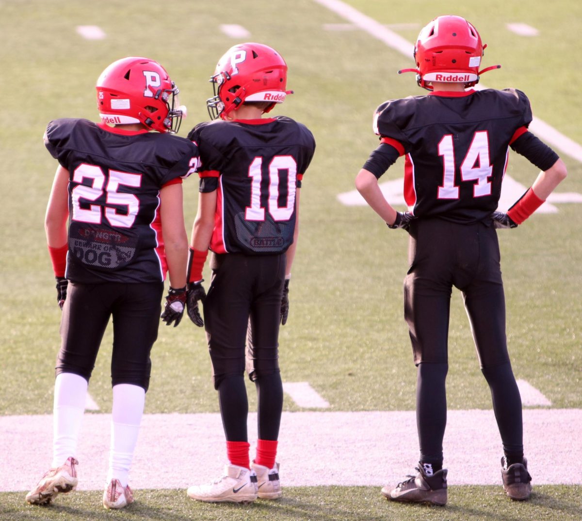 Brady Herman (25), Robert Metcalfe (10), and Jack Fonte (14) stand on the sideline during their last Pop Warner game in 2021. Metcalfe started playing at a young age but stopped playing his freshman year. (Courtesy of Noreen Chung)