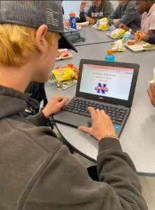 Noah Zupan, a Nonnewaug junior, looks at the 2024-25 student handbook reviewing the new policies being enforced for underclassmen.