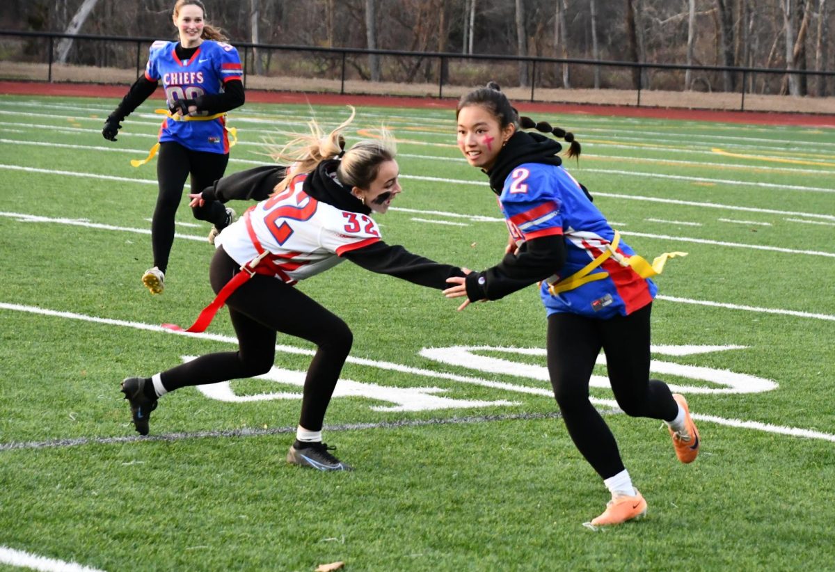 Ellie McDonald (2) runs with the ball as Gianna Geraci tries to catch her during the 2024 juniors vs. seniors powderpuff game on Nov. 25.