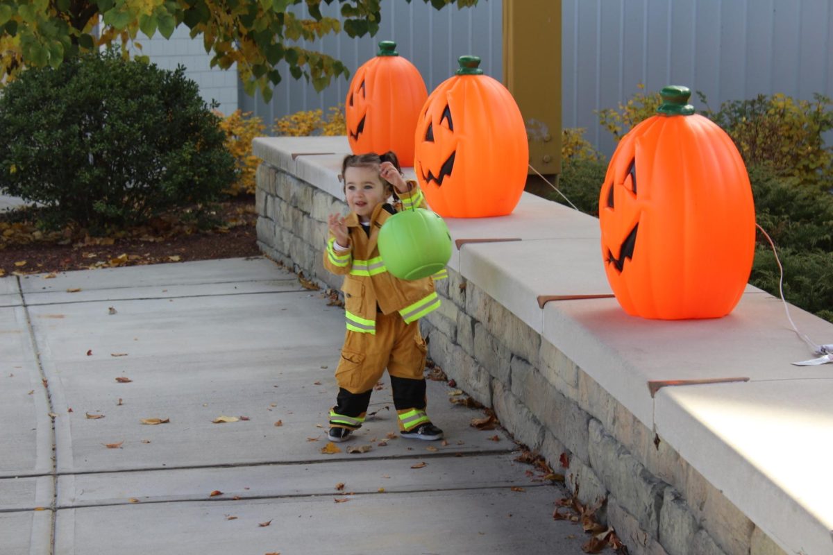 Student Council advisor and science teacher Joshua Kornblut’s daughter, Brooke Kornblut, grabs a jack-o-lantern at Trick or Treat Street on Oct. 26 at Nonnewaug. 