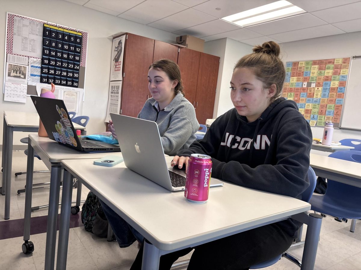 From left, senior Ashlynn Graziano and sophomore Elliana Obolewicz use their personal computers to complete assignments. Even though Nonnewaug provides Chromebooks for school work, many students use their own devices.