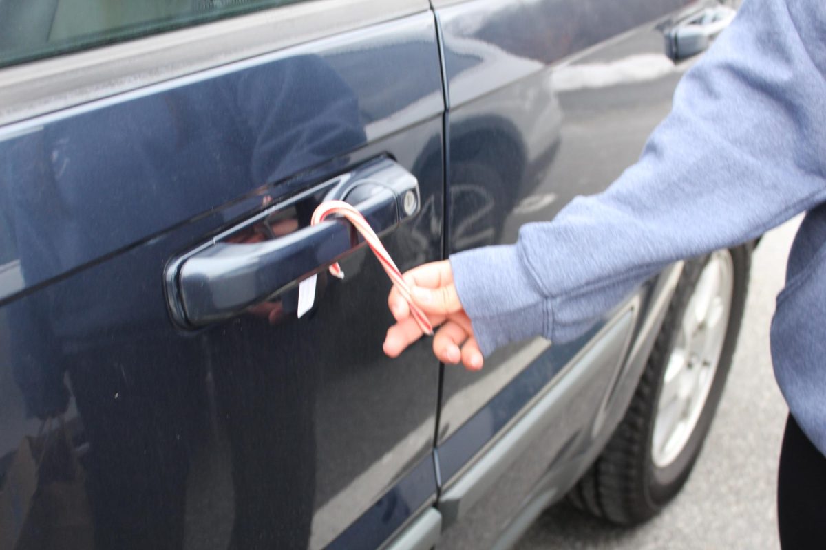 President of Student Council Ada Gorka places a candy cane onto a car door handle at Nonnewaug High School on Dec. 20.