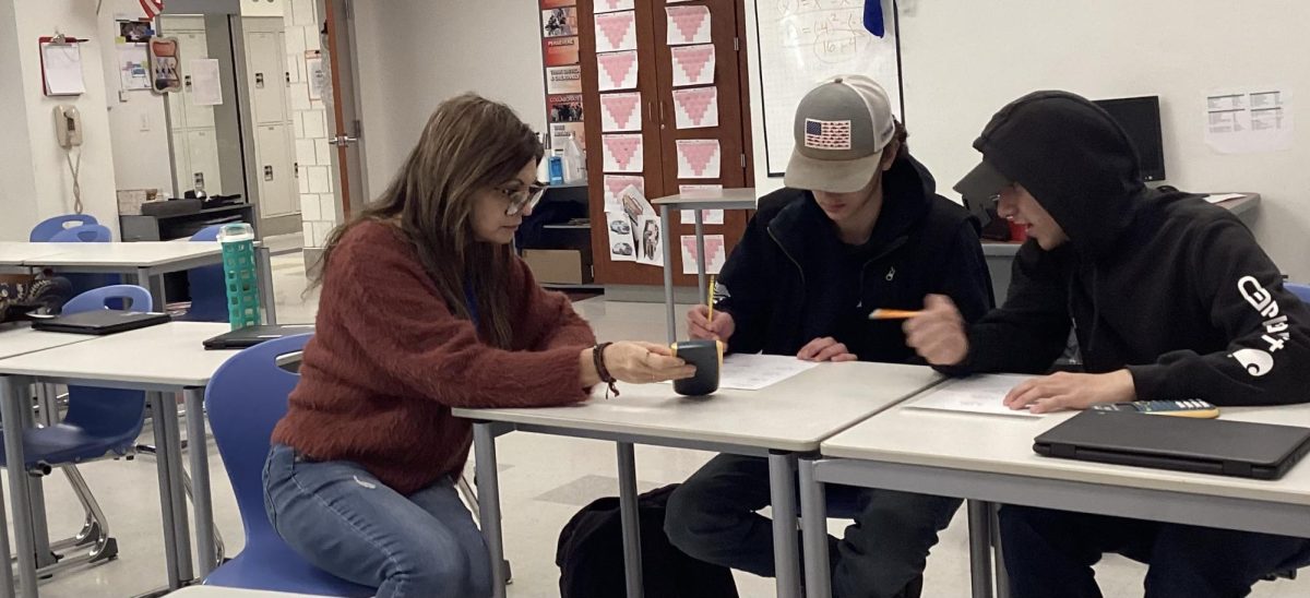 Teresa Kelly works through school work with students (left to right) William Martino and Gerry Ruiz. Kelly's desire to help her students motivates them to complete their school work.