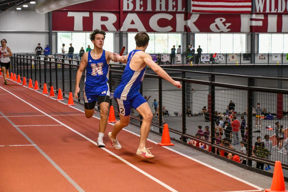 Thatcher Budris passes the baton to Jake Cenatiempo in the boys 4x200 meter relay on Feb. 1 during the Bethel Indoor Invitational.