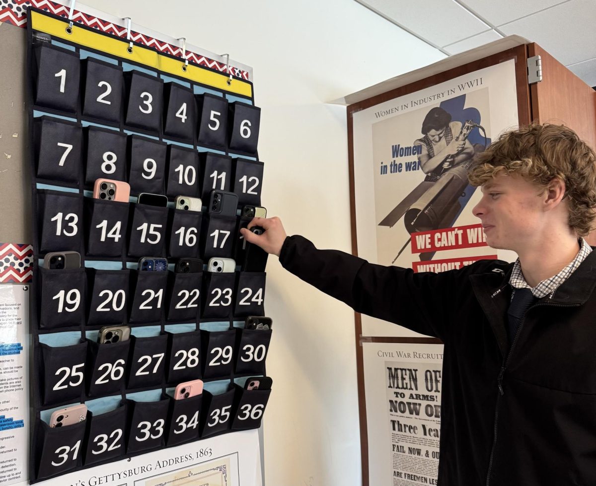 Matthew Molleur, a junior at Nonnewaug, puts his cellphone into his assigned pocket in the phone holder. He does this each class to make sure that his attendance stays good and he doesn’t get distracted in class.