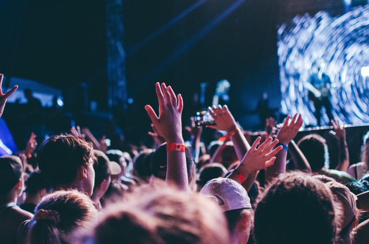 Crowd at a concert raising their hands and listening joyfully to the live music on stage. NHS students have a wide variety of musical tastes, but similar to many people, exploring others' favorite artists makes people hesitant. Photo Credit: Alex Bracken (Unsplash)