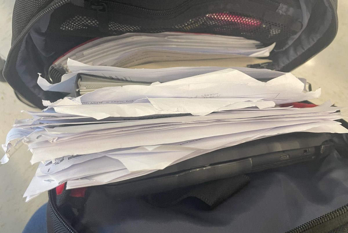 Adrienne Coelho quickly stores miscellaneous papers into her backpack rather than neatly organizing them with a binder.