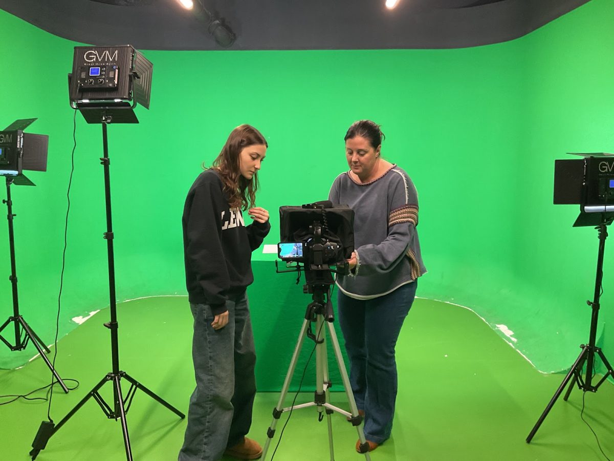 Video production teacher Katie Blake, right, shows senior Zodie Smith how to work with the camera in the green screen room.
