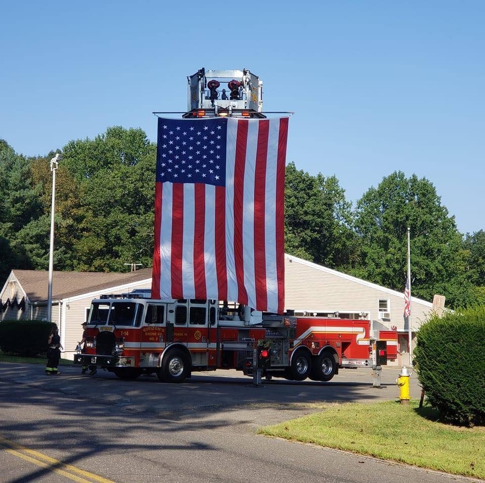 Seymour Fire’s ladder truck holds up an American flag for a memorial at Great Hill Hose Co. The lack of firefighters shown in the picture shows rapid decrease of fire support. (Courtesy of Seymour Fire/Facebook)