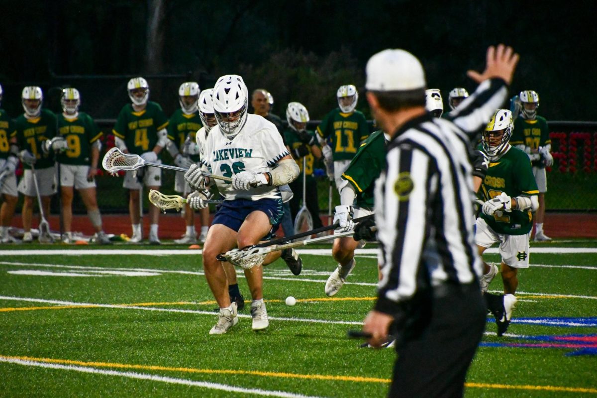 Matthew Paolino (26) Looks down to scoop the ball as the ref calls a push from behind? on May 7th during the Lakeview boys lacrosse Co-op game against Holy Cross.