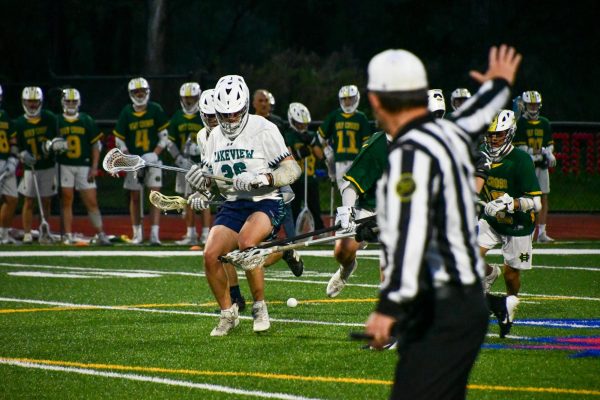 Matthew Paolino (26) Looks down to scoop the ball as the ref calls a push from behind? on May 7th during the Lakeview boys lacrosse Co-op game against Holy Cross.