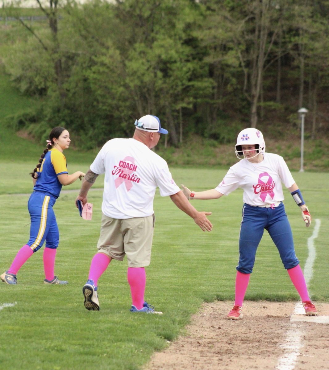 Nonnewaug freshman Lila Farrelly high fives coach Chris Martin after her triple during the NHS softball game on May 9. 
