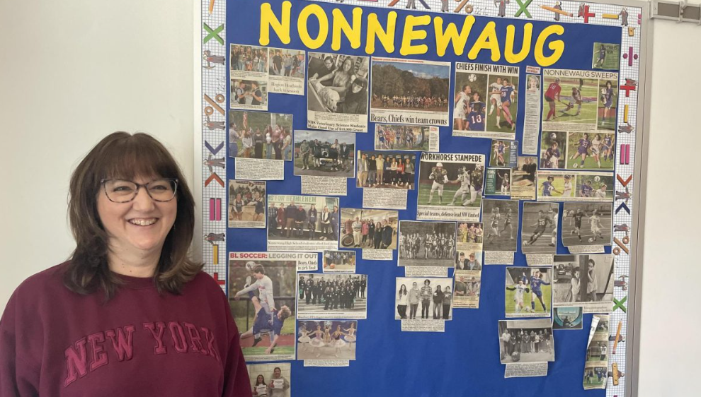 Math teacher Laurenn Bertoglio poses next to one of her bulletin boards displaying the accomplishments of many of her students at Nonnewaug. (Gianna Lodice '24)