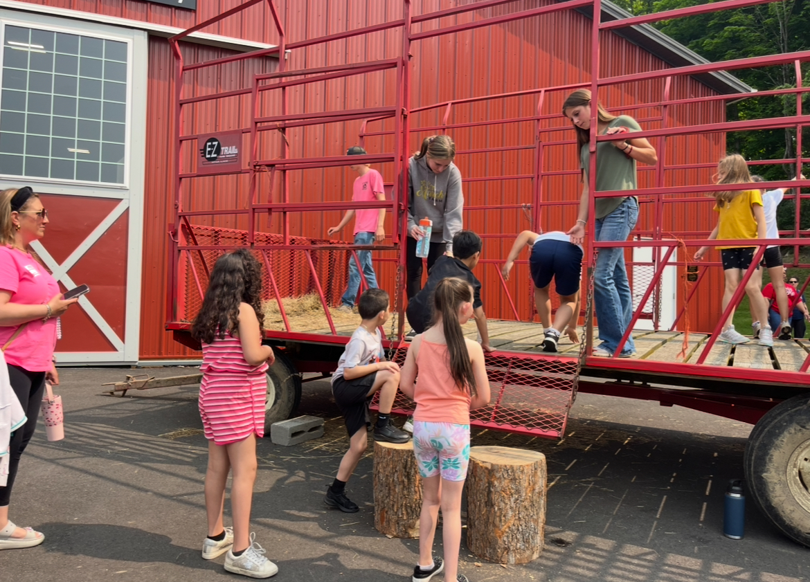 Juniors Lainey Scanlon and Tess Cuccia help younger students onto the hay wagon.