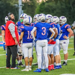 Scott Lynch, Nonnewaug's newest addition to the coaching staff, stands with his team before a game. NHS football is one of many teams adapting to new coaching this season. (Courtesy of Noreen Chung)