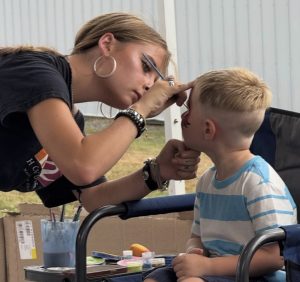 Junior Greta Addeo painting a little boy's face during the Bethlehem fair. This is one of many opportunities Nonnewaug students have to display their artistic abilities. (Courtesy of Greta Addeo)