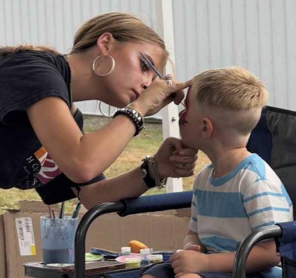 Junior Greta Addeo painting a little boy's face during the Bethlehem fair. This is one of many opportunities Nonnewaug students have to display their artistic abilities. (Courtesy of Greta Addeo)