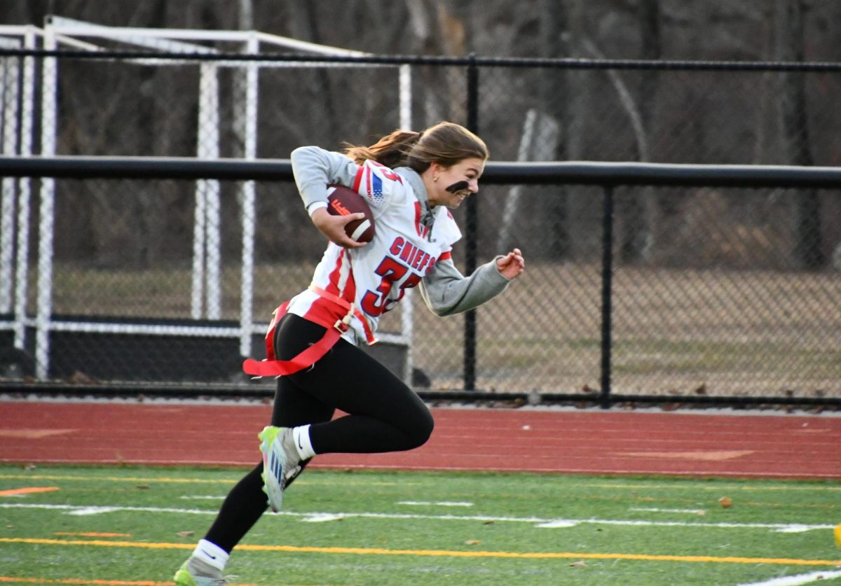 Senior Ella Quinn runs with the ball in last year's Powderpuff Football Game. The juniors had an upsetting loss over the seniors, but hope to secure a win this year.