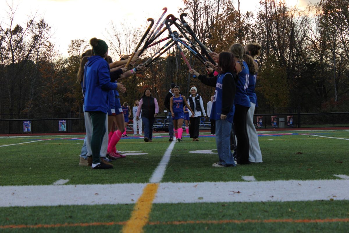 Sophia Garguilo (3), a senior at Nonnewaug, walks through a tunnel made of field hockey sticks with her mother and sister (Madeline Garguilo).