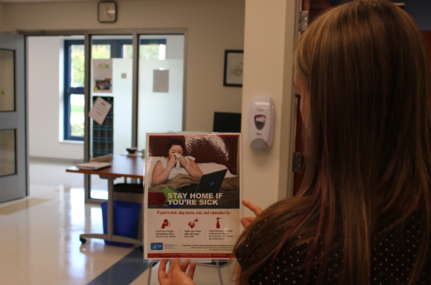 An NHS student looks onto a sign in Nonnewaug’s nurse’s office informing students to stay home if you're sick. This is an important saying throughout the school as the first wave of illnesses hits campus this fall. 