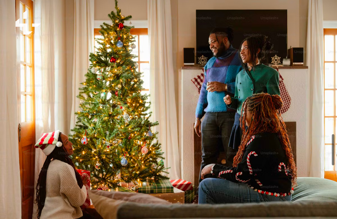 A family sits around a tree they have just decorated together and gaze at it with admiration. (Courtesy of Michael T via Unsplash)