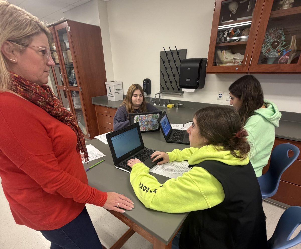 Stone helps biology students Jocelyn McDougall, Alaina Ambrosio, and Gianna Perugini get started with their assignment the study of Punnett Squares. In typical Stone fashion, she always makes an effort to circulate around the classroom to ensure that everyone gets the help they need.