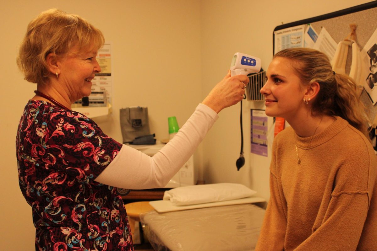 School nurse Sandy Snabaitis checks Aubrie Salisbury‘s temperature amid this winter’s flu and cold season. Many sick kids come to her for aid, and about five kids leave school with a sickness per day during this period.