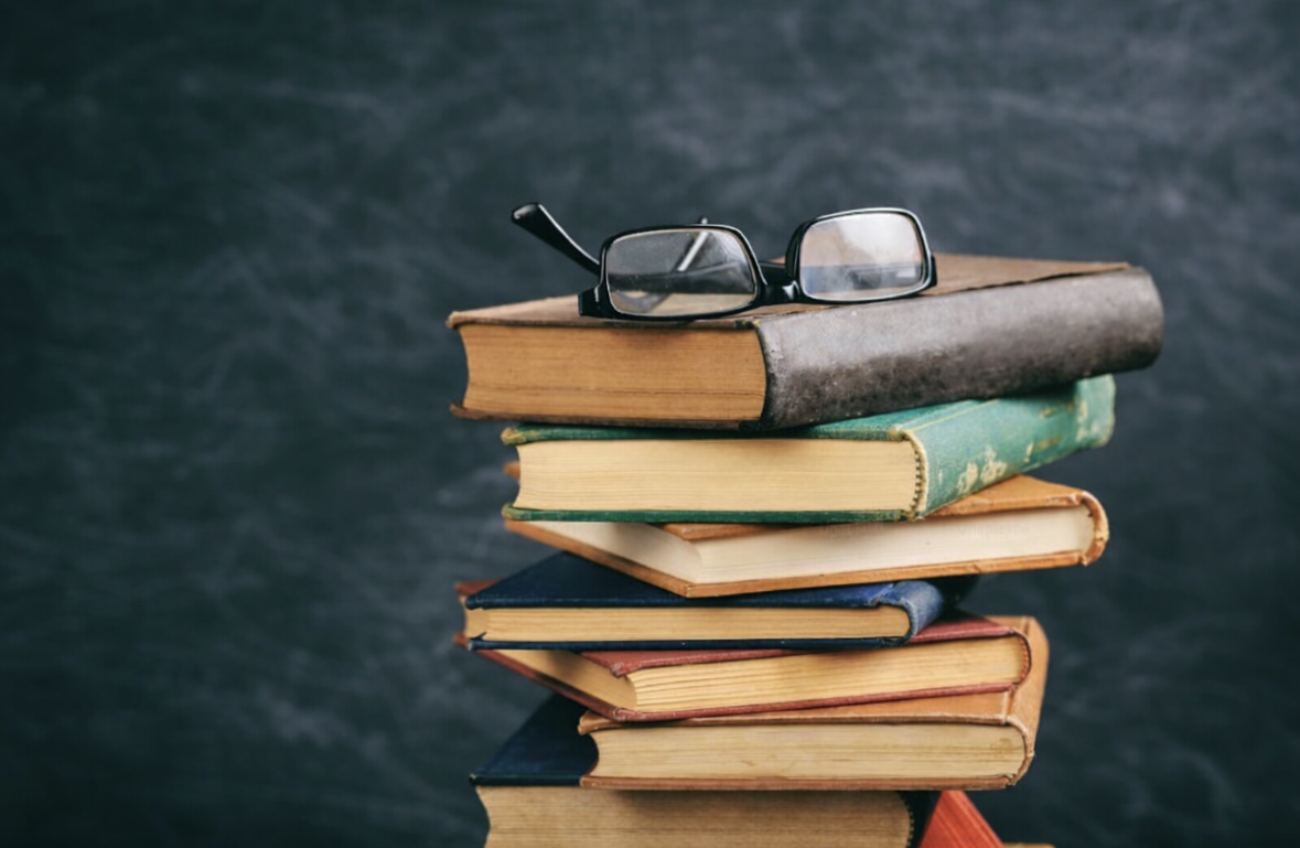 A stack of books sits with a pair of glasses on top. Literature is very important for human brain development. (Courtesy of Unsplash)