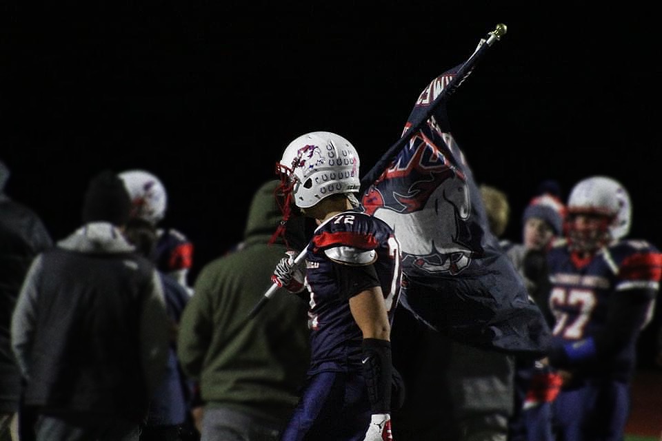 Charles Rickenbach carries a Northwest United Workhorses flag in 2021. Rickenbach was a former football player who played for both the original Nonnewaug Chiefs and Northwest United football programs. As a football player, he constantly deals with situations that can affect his mental health. Rickenbach just finished his fourth season at University of New Haven where he, too, experienced the emotional rollercoaster that comes with being an athlete. (Photo Credit - Charles Rickenbach)