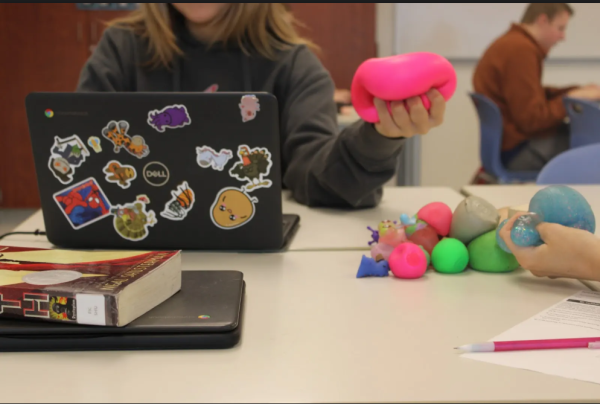 An NHS student squishes and stretches a bright pink Needoh while completing a homework assignment. These fun colored stress balls are a great way to keep students from fidgeting while completing their work.