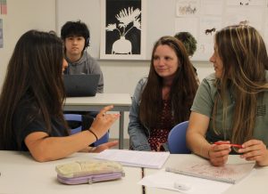 NHS English faculty member Maura White sits with a pair of her creative writing students Isabella Criscione (left) and Sophia Lopez (right). Throughout her most than two decades in the English department, White is known for her caring personality and passion for all things poetry.